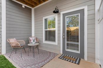 a front porch with two chairs and a table and a door